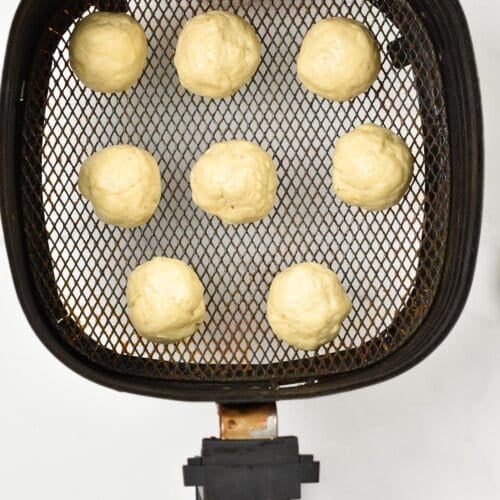 Banana donut hole in the air fryer basket before being air fried.