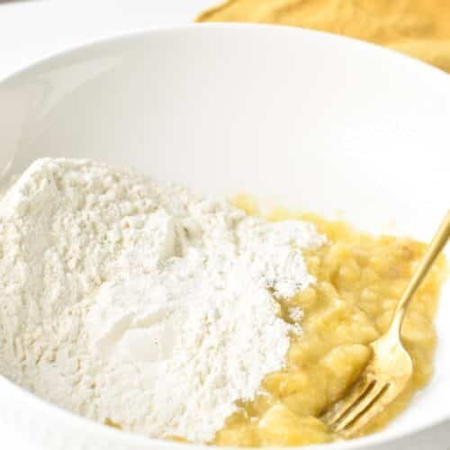 A bowl with a golden fork, mashed banana and self raising flour.
