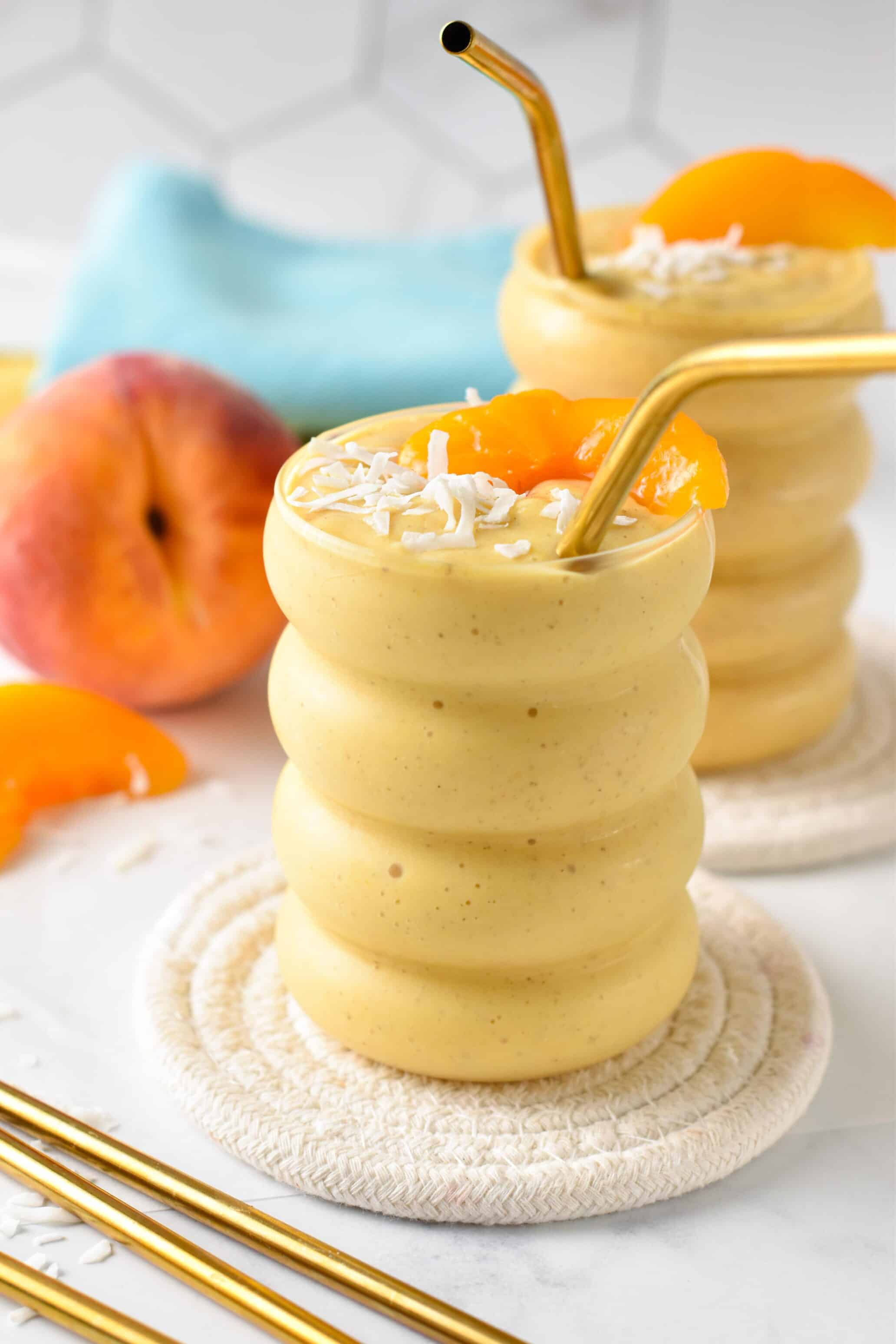 Banana Peach Smoothie served in a curved glass with a golden straw.