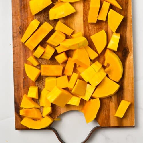 a wooden chopping board with pieces of butternut squash