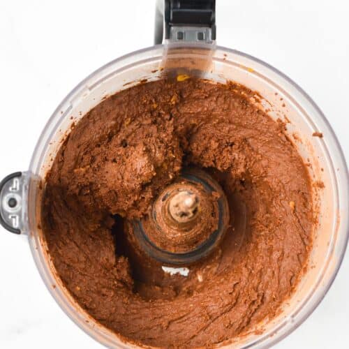 A food processor bowl with thick chocolate brownie batter.