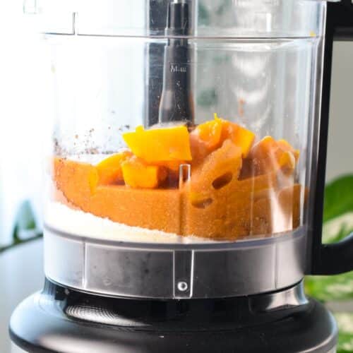 A food processor bowl filled with oat flour, almond flour, butternut squash and peanut butter.