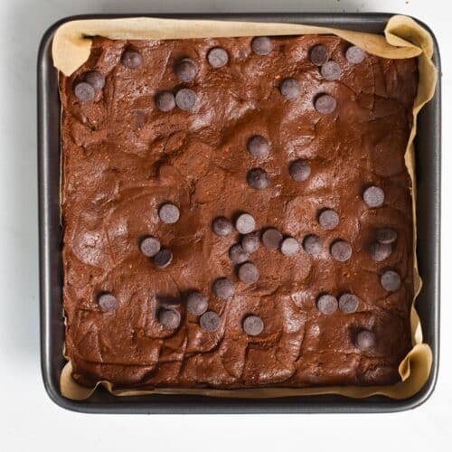 A brownie pan filled with brownie batter and chocolate chips on top.