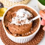 a spoon digging in a bowl filled with chocolate mousse and coconut yogurt.