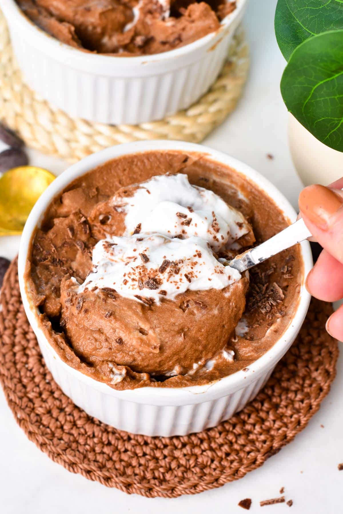 A spoon digging in a bowl filled with chocolate mousse and coconut yogurt.