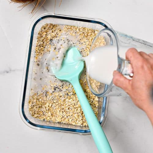 Pouring coconut milk on Overnight oats with coconut milk ingredients.