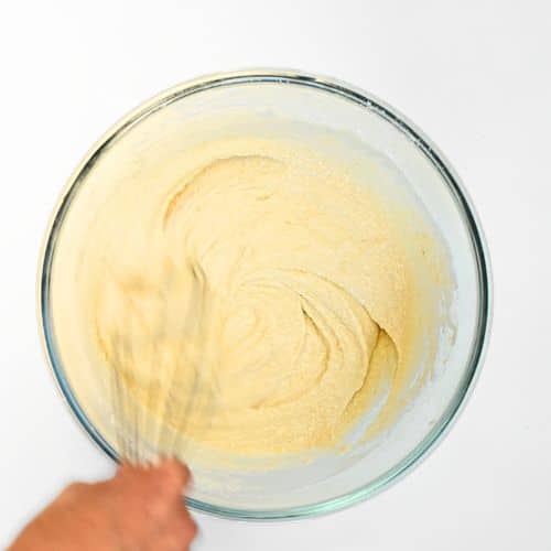Mixing the paleo pancake batter in a mixing bowl with a whisk.