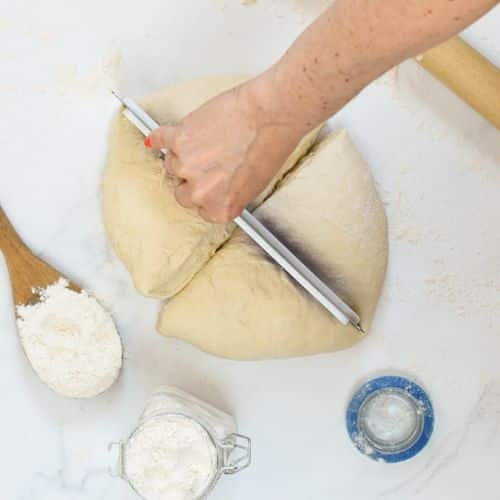 Cutting the vegan pizza dough into four identical parts.