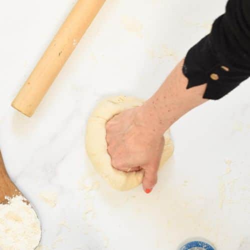 Rolling a pizza dough ball to make a vegan pizza crust.