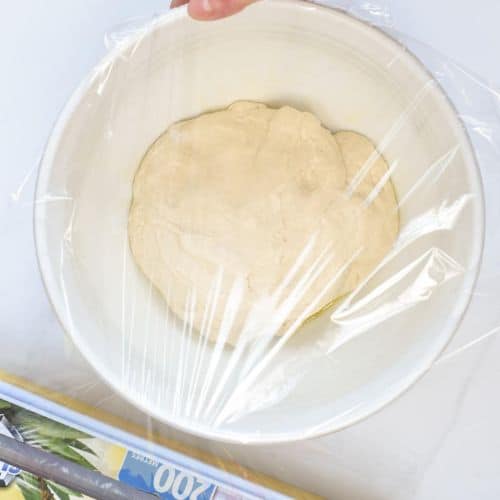 Covering the bowl with vegan pizza dough with wrapping paper