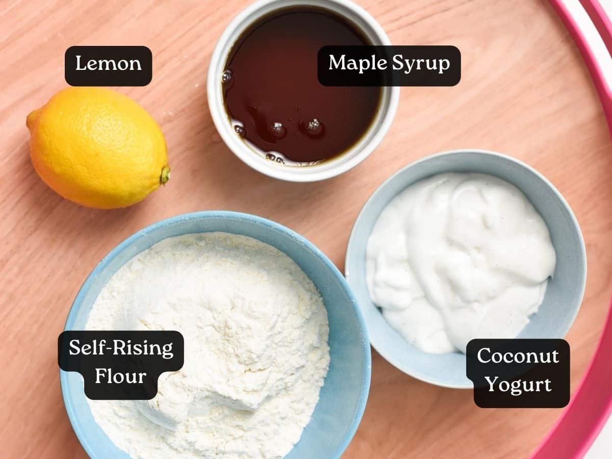 Ingredients for 4-ingredient Lemon Cake in small bowls: maple syrup, coconut yogurt, lemon, self-rising flour.