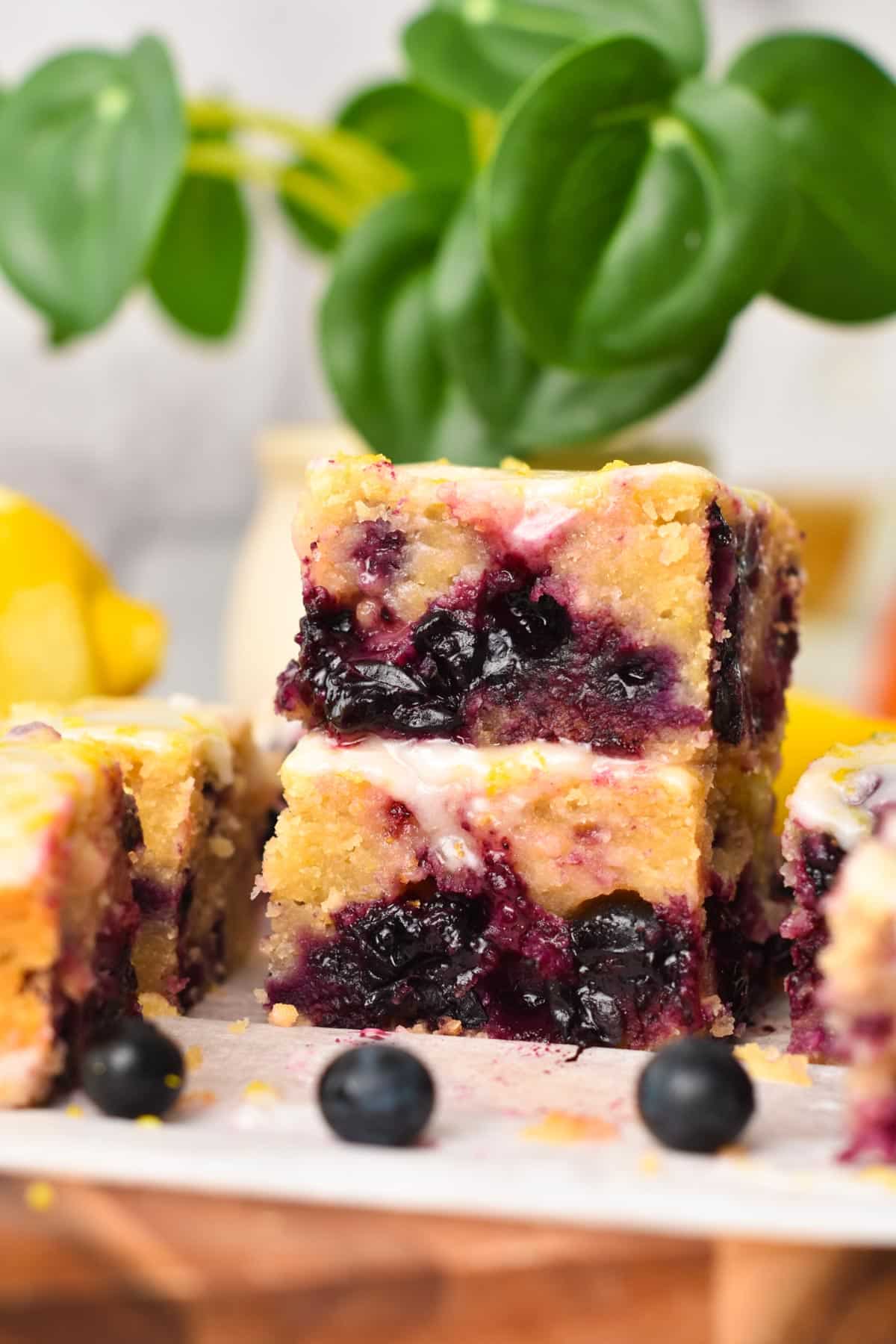 A stack of three pieces of lemon blueberry blondies with icing.