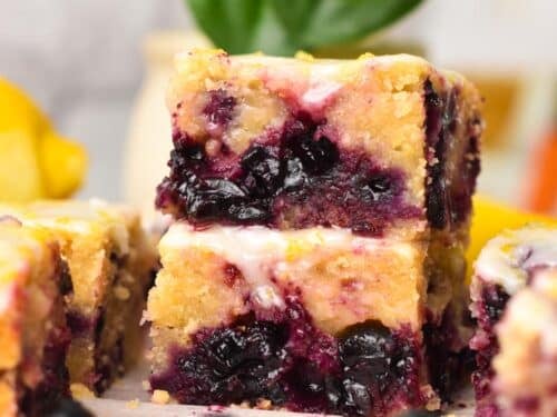 a stack of three pieces of lemon blueberry blondies with icing