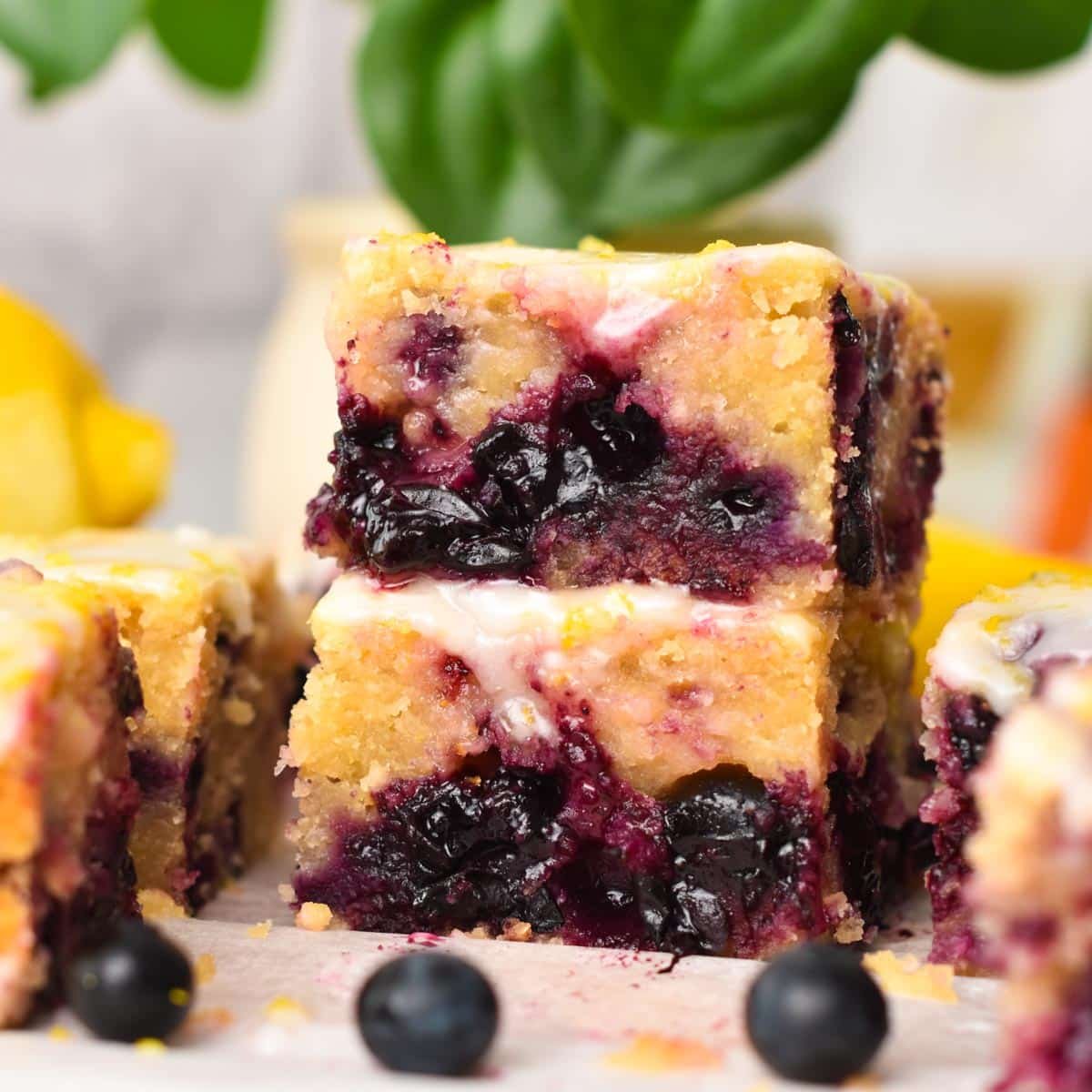 a stack of three pieces of lemon blueberry blondies with icing