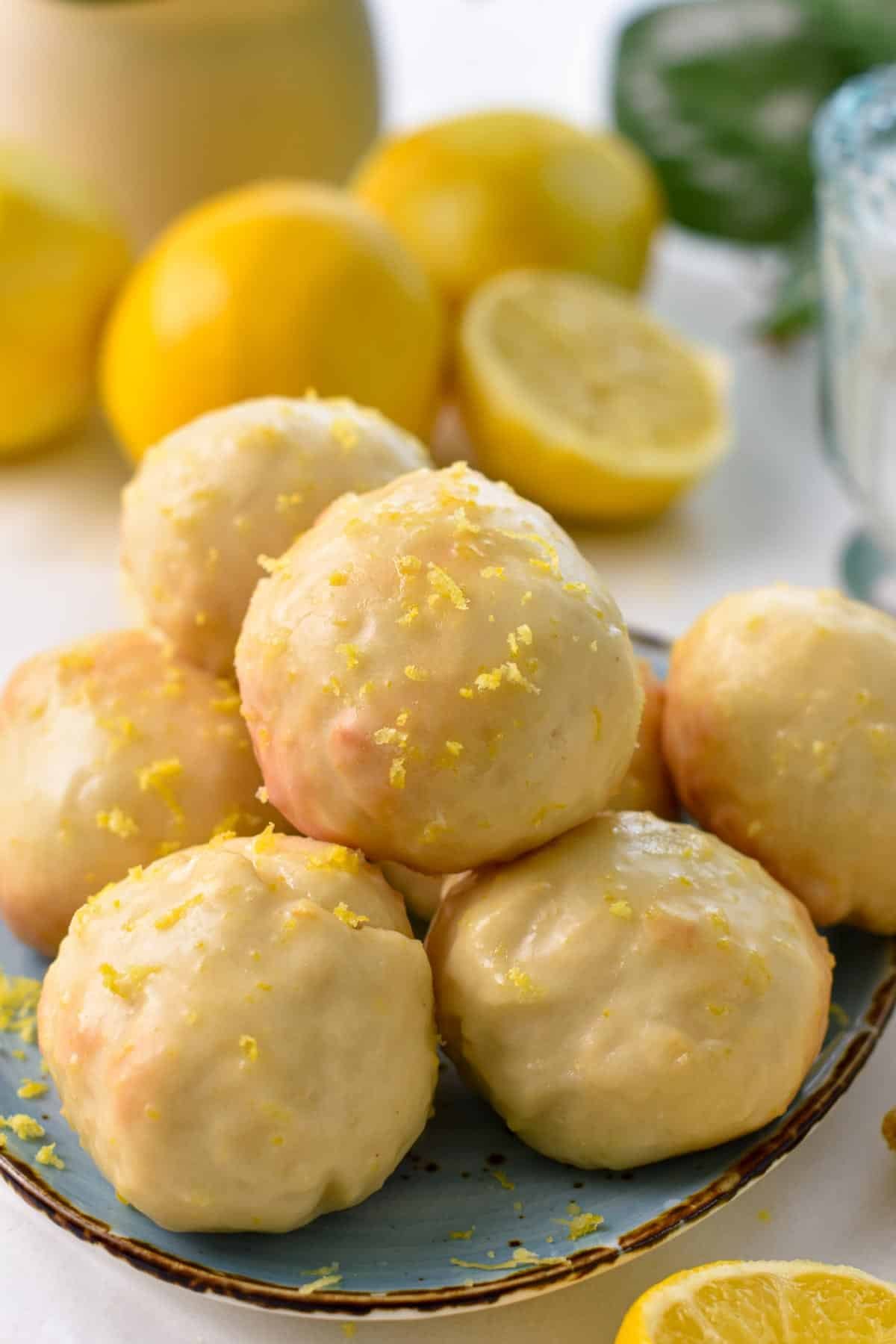 A stack of lemon donut holes glazed with lemon icing and lemon zest on top.