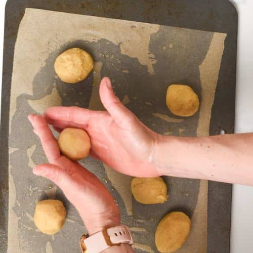 Rolling 2-ingredient cookies on a baking sheet.