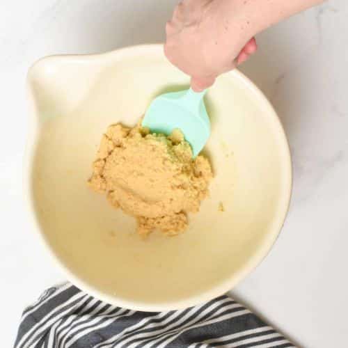 Combining 2-ingredient cookie batter in a large mixing bowl with a silicone spatula.