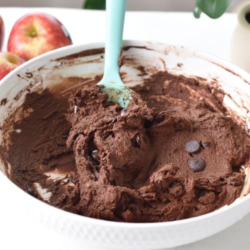Applesauce brownies batter stirred with a silicone spatula in a bowl.