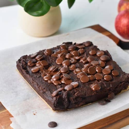 Cooked applesauce brownies on a baking sheet on a chopping board.