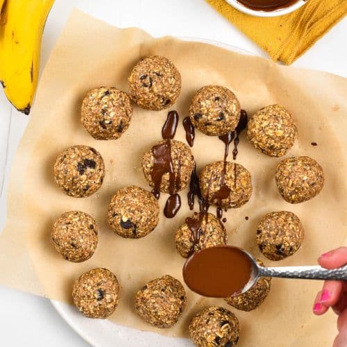 Pouring melted chocolate on top of the Banana Oat Balls.