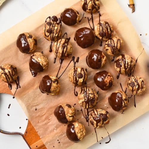 Banana Protein Balls on a chopping board lined with parchment paper.