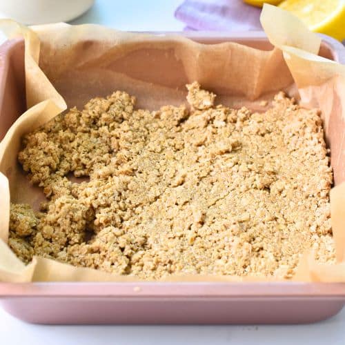 Pressing the Blueberry Breakfast Bars crust in a square pan.