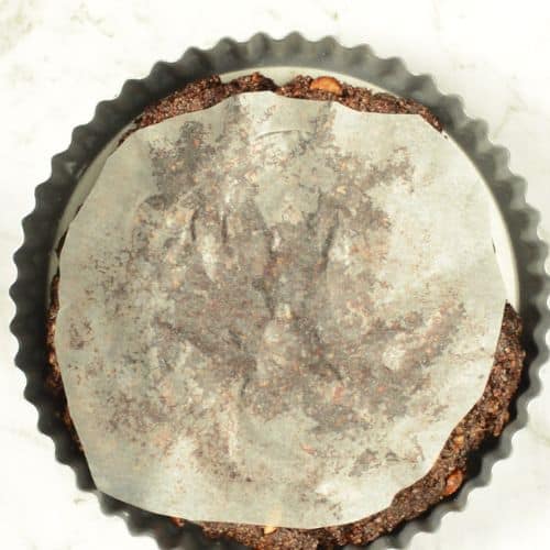 Chocolate Avocado Pie crust in a large pan covered with parchment paper.