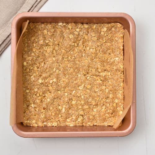 Peanut oatmeal mixture pressed in a square baking pan.