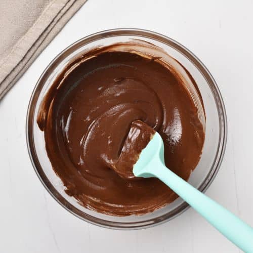 Spatula in melted chocolate in a large mixing bowl.