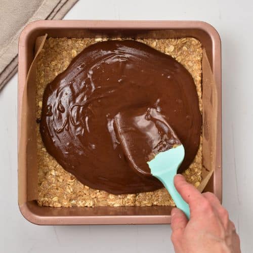 Spreading chocolate layer on top of the no-bake peanut butter base