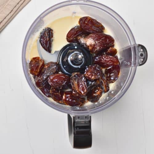 Dates and milk in the bowl of a food processor.