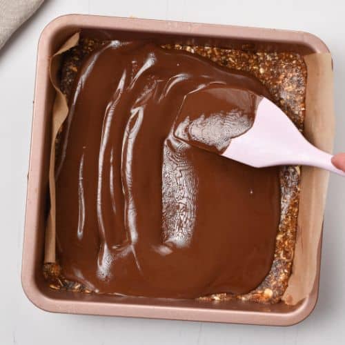 Pouring chocolate on the Healthy Date Bar base.