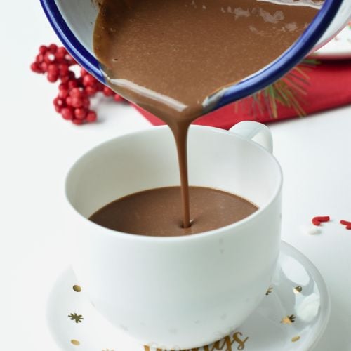 Pouring protein hot chocolate in a mug.