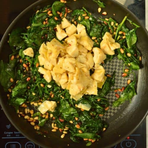 Cooking spinach and artichoke in a frying pan.