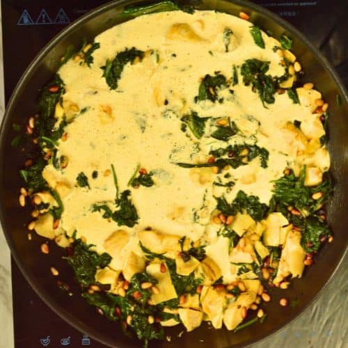 Cooking spinach, artichoke and pine nuts in a cashew sauce.