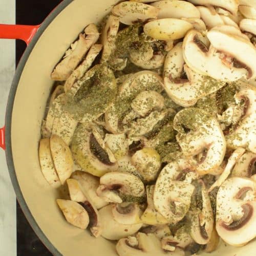 Cooking mushrooms in a large cast-iron pan.