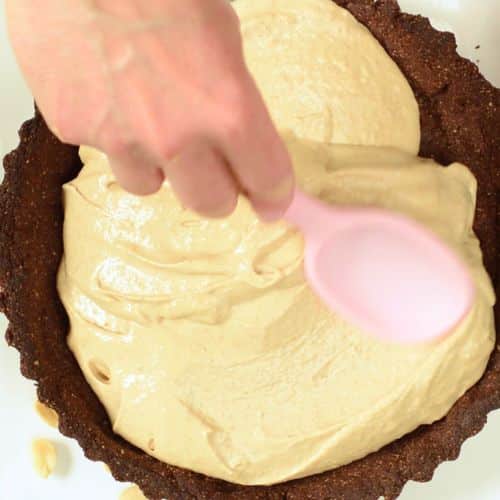 Spreading peanut butter filling on a no-bake vegan pean pie