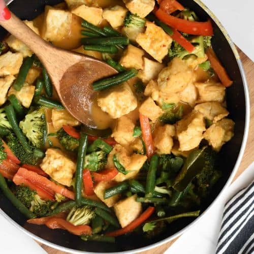 Tofu Red Curry ready in a pan with a wooden spatula.