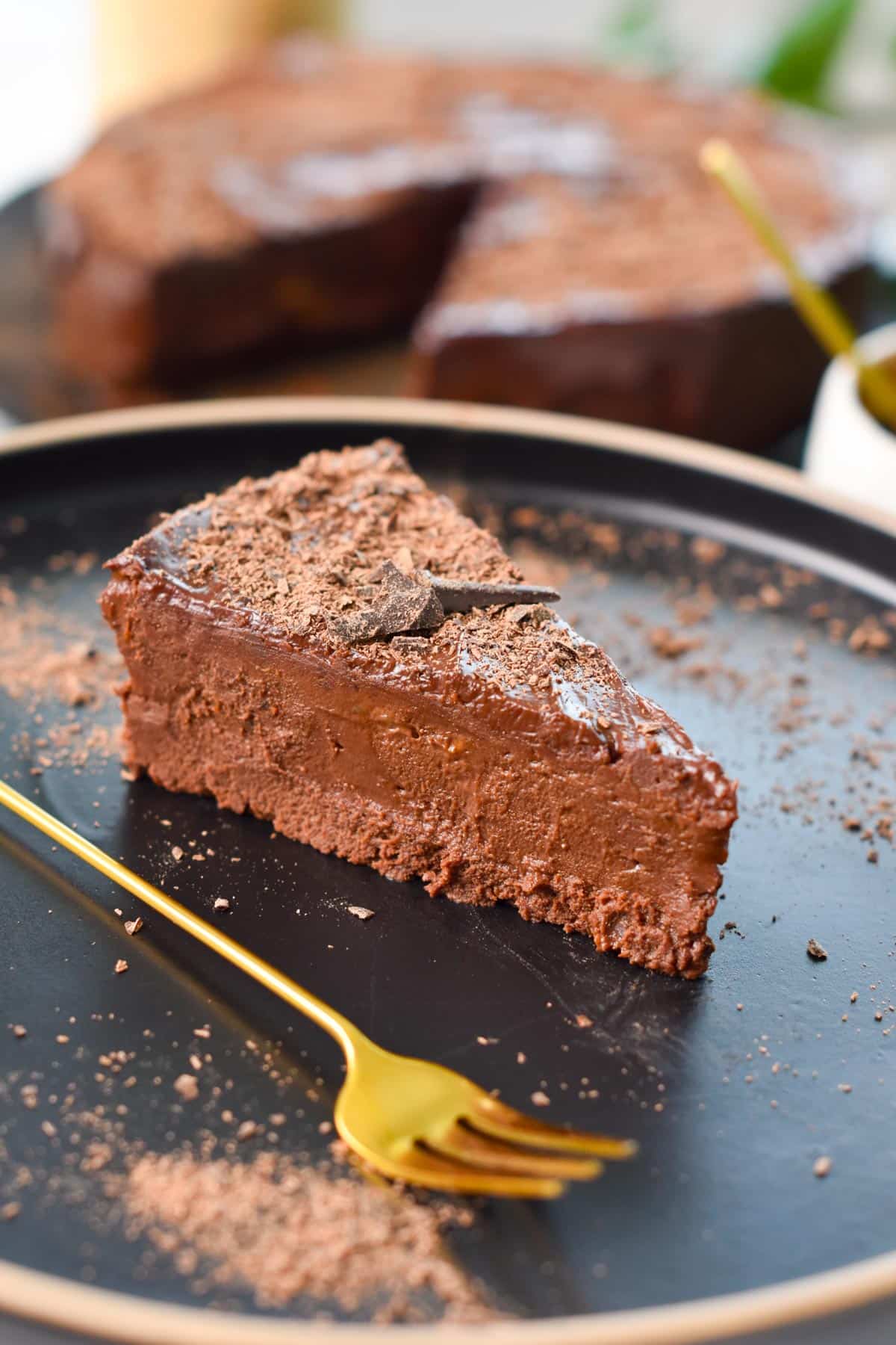 A slice of No-Bake Chocolate Cake on a black plate, with a golden fork on the side.