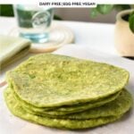 a stack of green spinach tortillas on a chopping board covered with white parchment paper