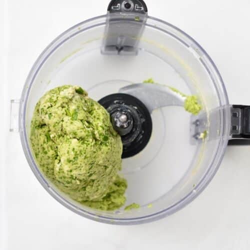 Green tortilla dough in a food processor bowl.