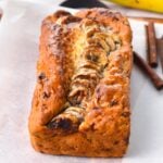 a banana bread on a chopping board with banana slices on top