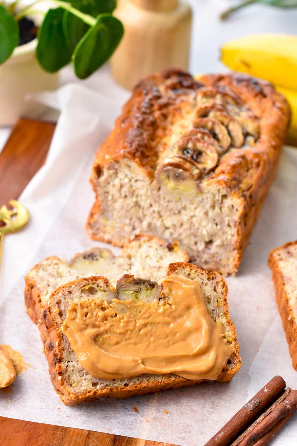 a banana bread sliced, with the front slice covered with peanut butter