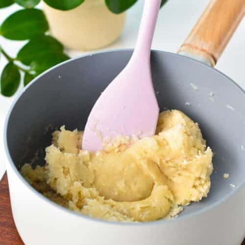 a churros dough in a non-stick saucepan with a rubber spatula in the saucepan