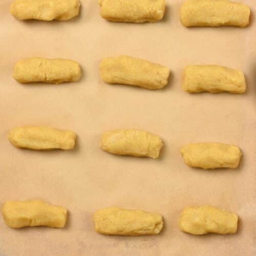 a baking sheet with small cylinders of almond flour cookie dough