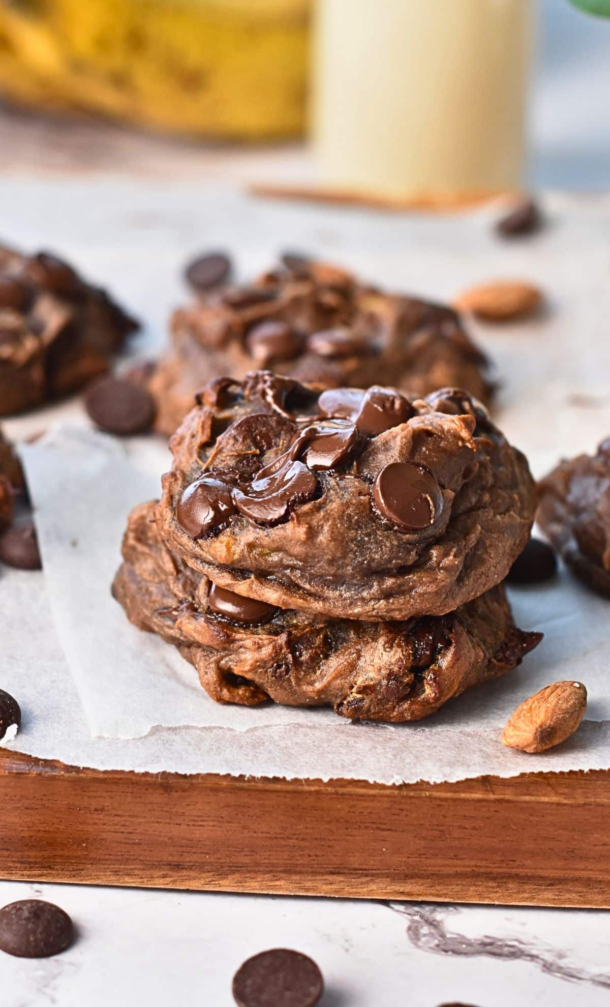 Two banana protein cookies stacked on a chopping board.