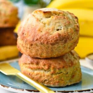 two bananas scones stacked, on a blue plate and a yellow knife on side
