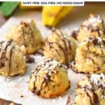 some coconut banana cookies with chocolate drizzle on top, on a wooden board covered with white parchment paper