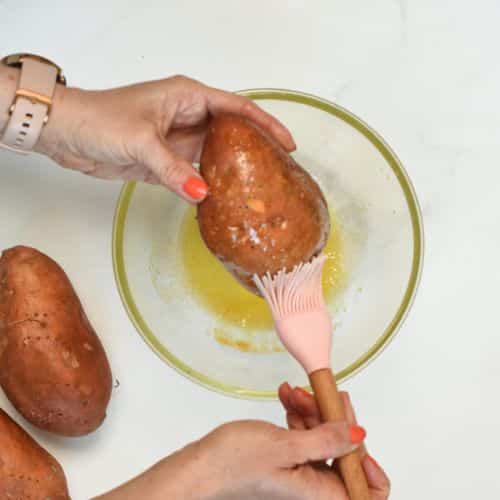 Brushing sweet potato with olive oil.