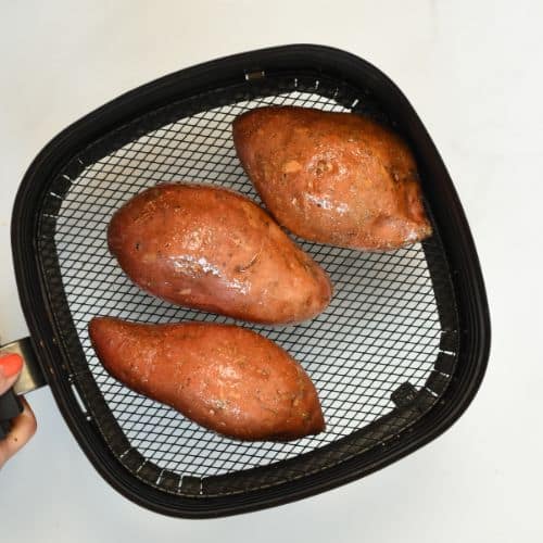 Sweet potatoes in the basket of an air fryer.